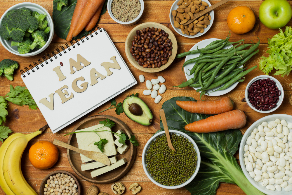 Avocado, almonds, bananas, and other vegan food items arranged on a table, representing a balanced vegan diet