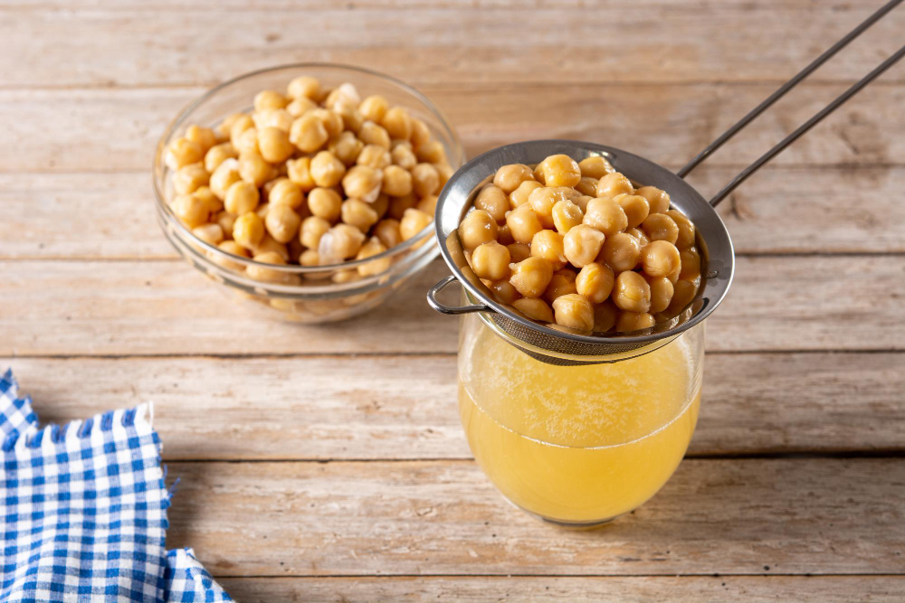 A glass cup containing aquafaba, a vegan egg substitute, with a creamy texture, captured against a neutral background