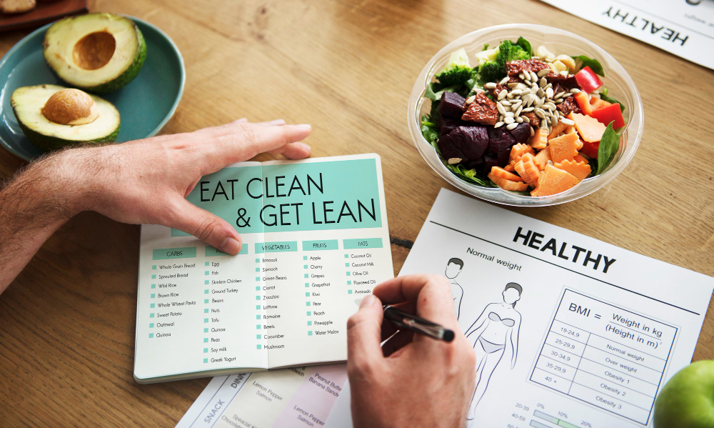 A person writing in a diary surrounded by a spread of vegan food, highlighting their journey with the vegan diet for weight loss