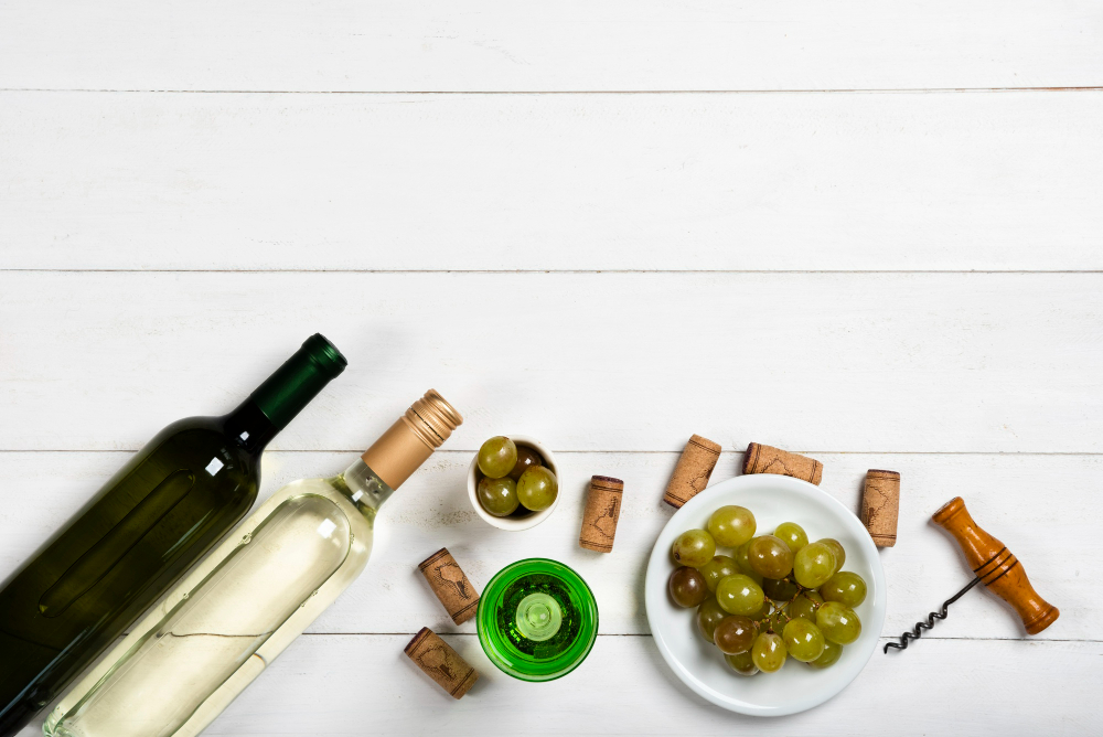 Bottles of vegan white wine stand beside scattered corks and a bunch of green grapes, highlighting vegan alcohol options