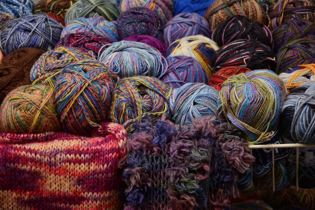 An assortment of colorful yarn balls and knitted fabrics, highlighting the variety of materials used in textiles and the search for vegan alternatives to wool.